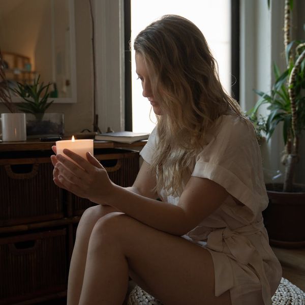Cozy corner of a room with a yoga mat, plant, and a candle.